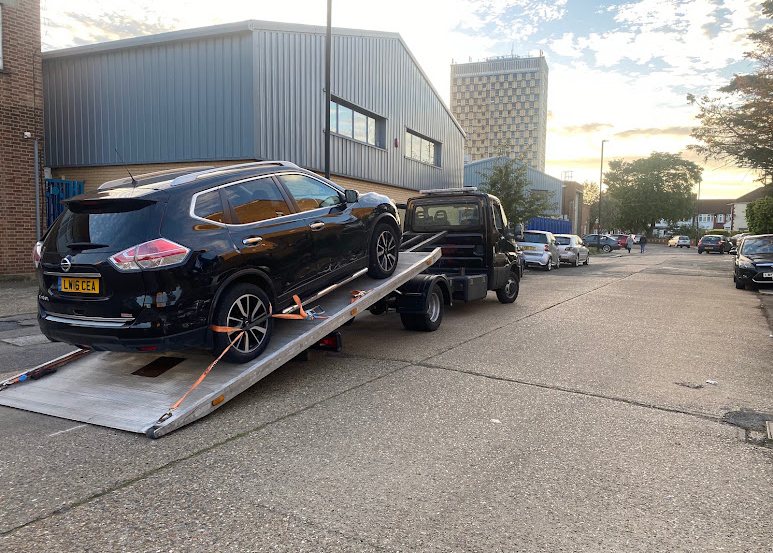 Black SUV strapped down on a tilt-bed recovery truck