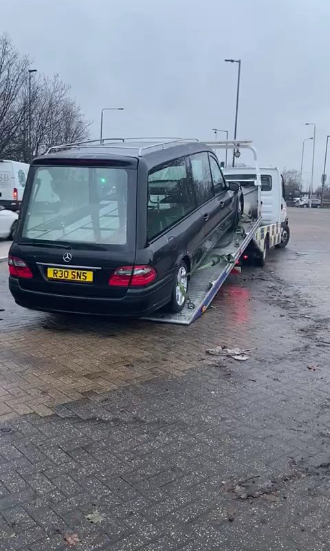 Hearse being loaded onto a tilt-bed truck